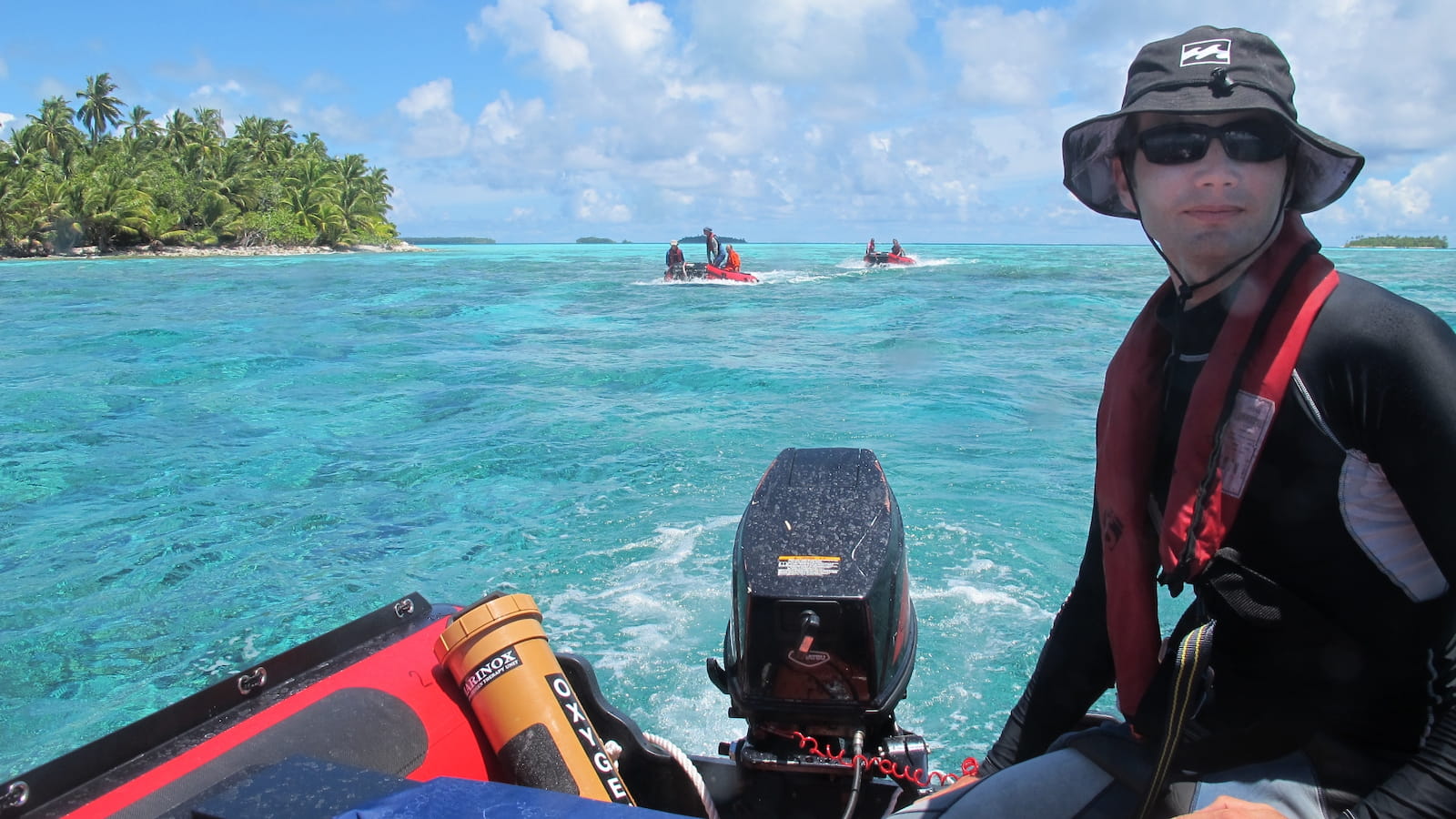 Professor Nick Graham pilots a small dinghy across bright blue seas