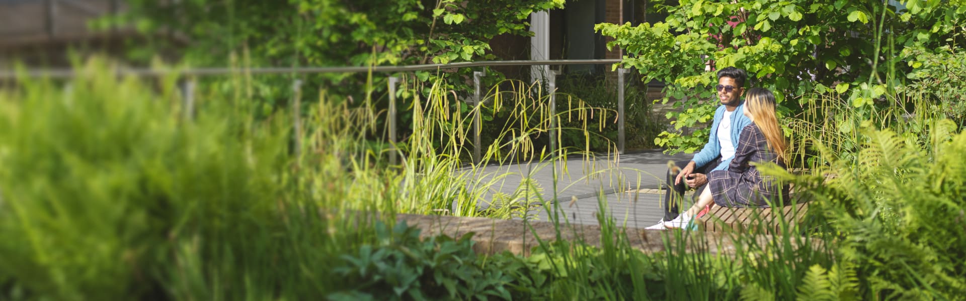 Two students sit surrounded by greenery