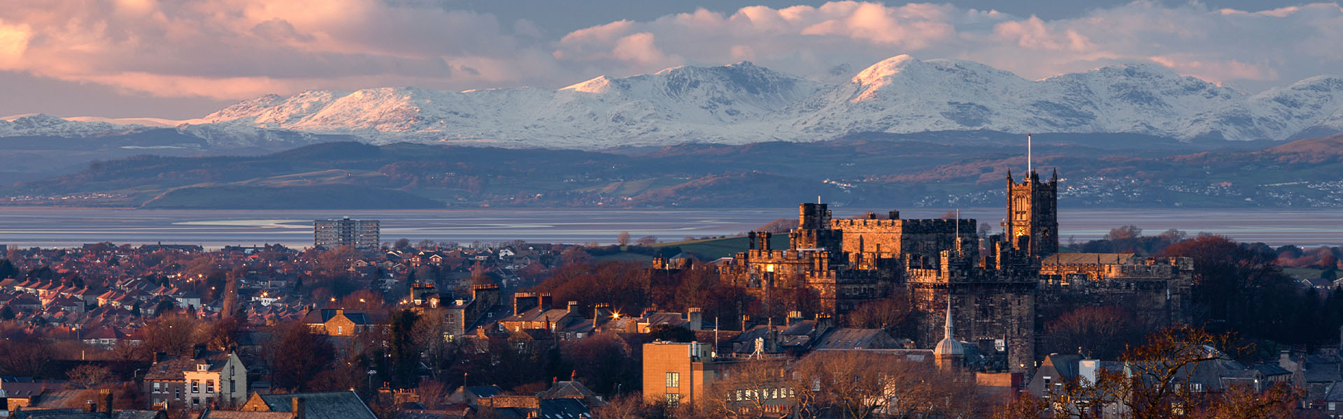 Lancaster skyline at sunset with snow-clad mountains in the background