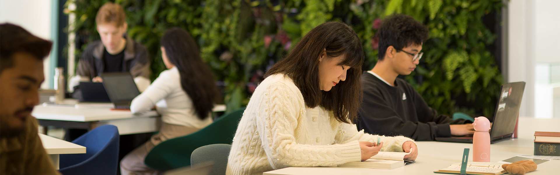 Students in front of the green wall in the University Library