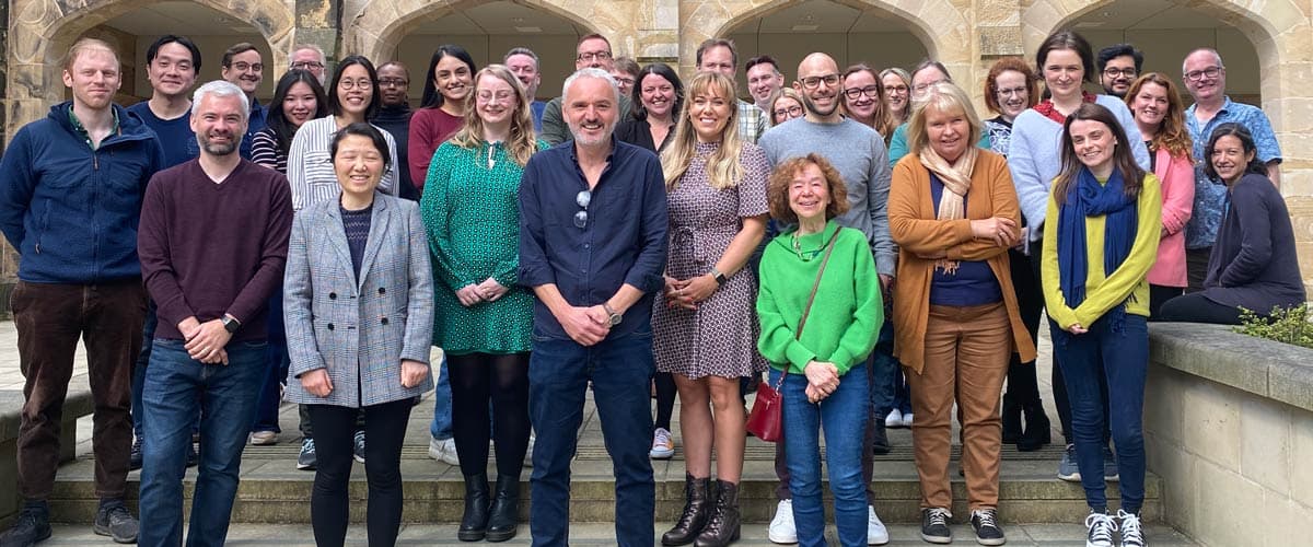 Group photo of around 30 School of Law staff with Lancaster Castle in the background