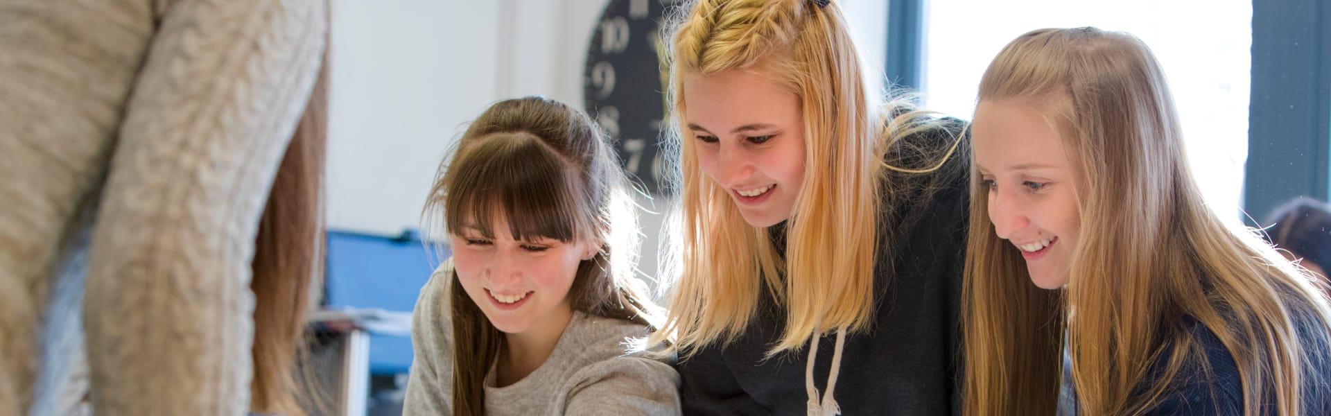 Three students smile and point to places on a map