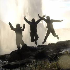 Three silhouettes jumping with a volcanic eruption in the background