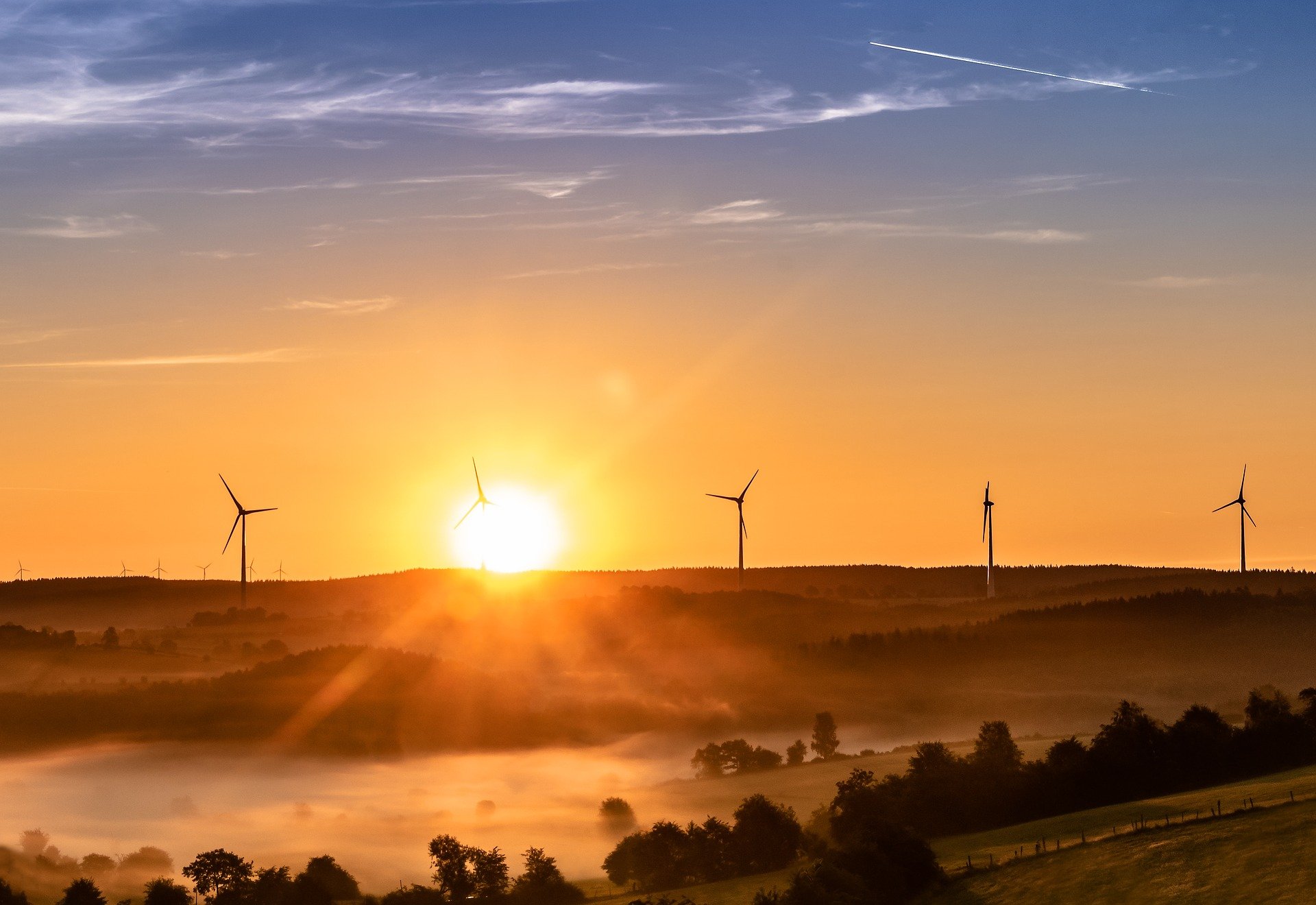 Wind turbines in a misty rural landscape at sunrise