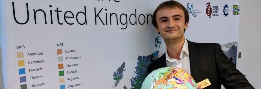 Dan Evans holds a globe showing soil types across the world