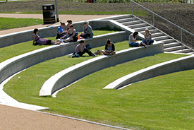 Image of steps on the university campus with students sat on them in the sun. 