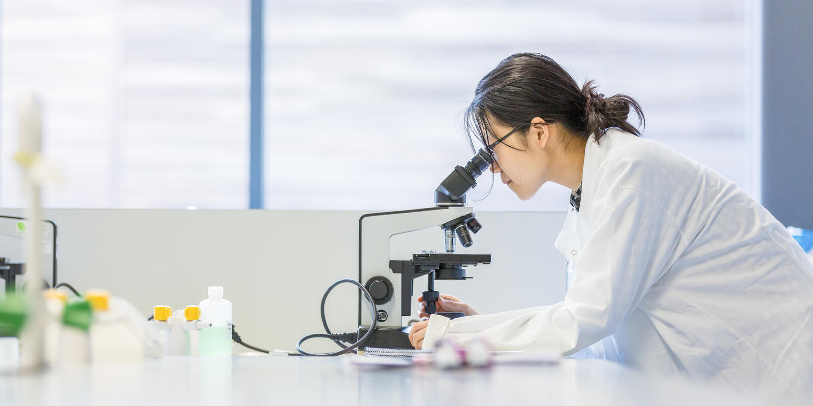 Researcher looking into a microscope in a laboratory.