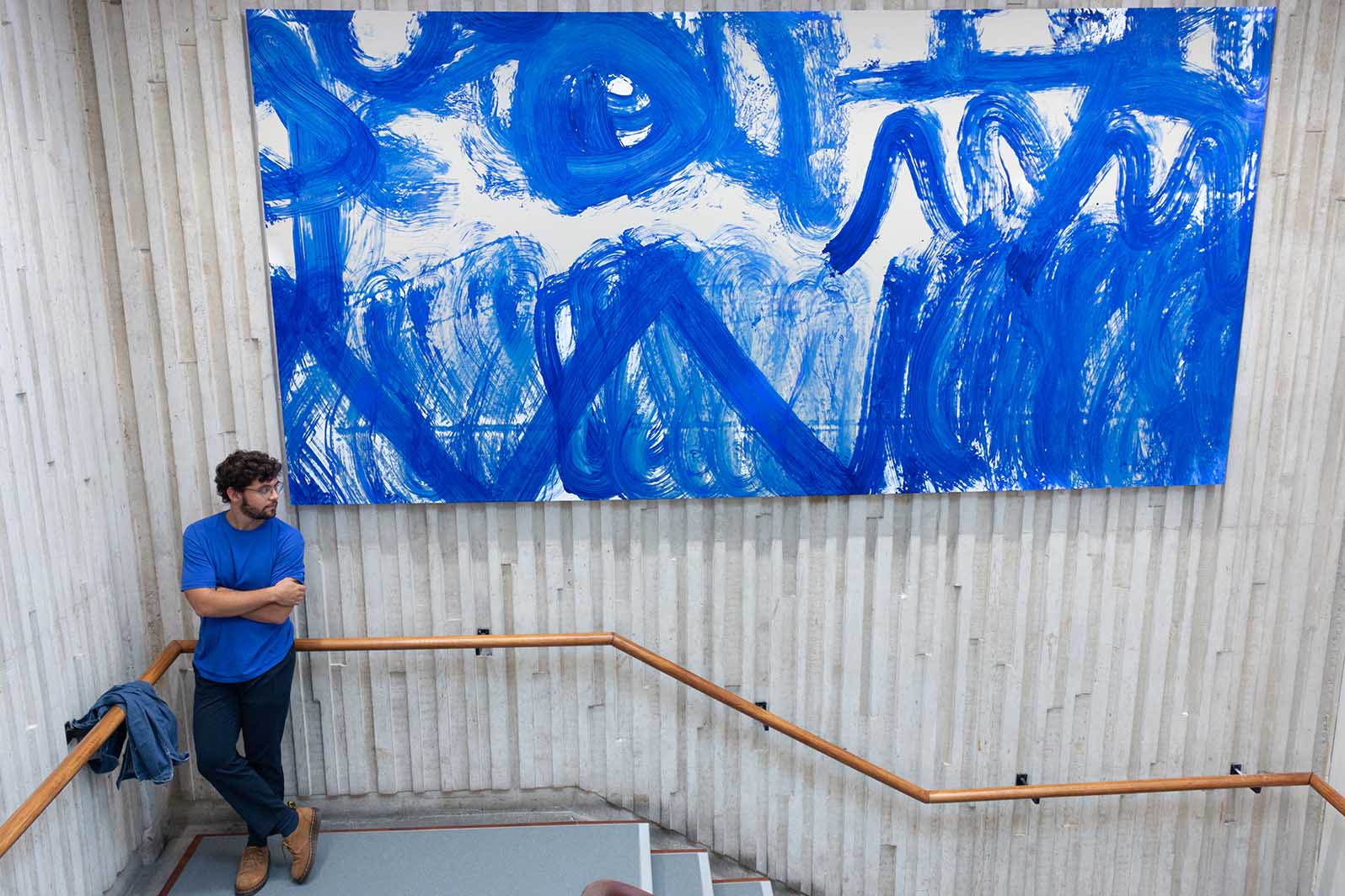 José Garcia Oliva standing beside one of the canvases created by Lancaster cleaning staff