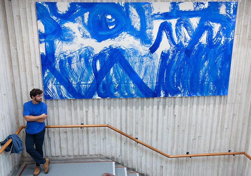 José Garcia Oliva standing beside one of the canvases created by Lancaster cleaning staff