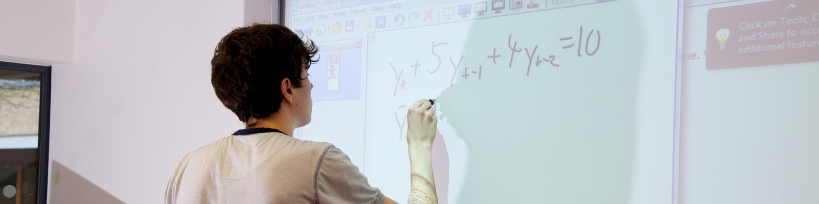 student writing formula on whiteboard