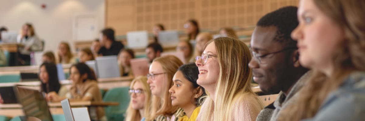 A row of students listens in a lecture theatre.