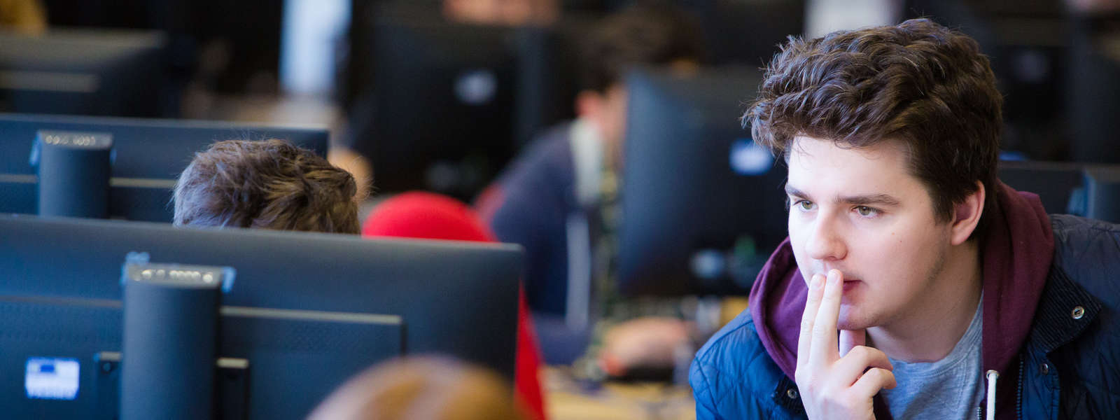 Student staring at a monitor with two fingers on his lips. 