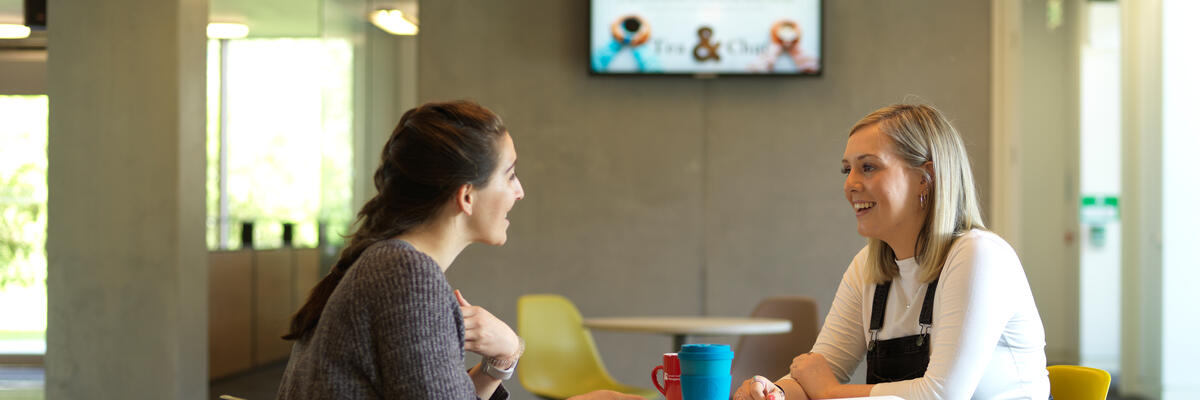 Two female students sta across a table talking