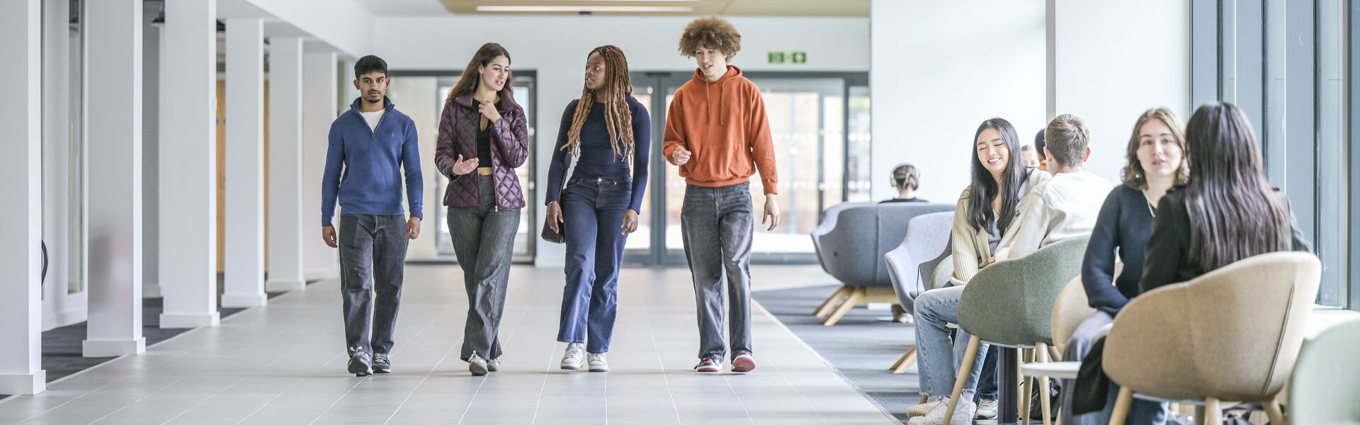 A group of students walking through the Management School chatting