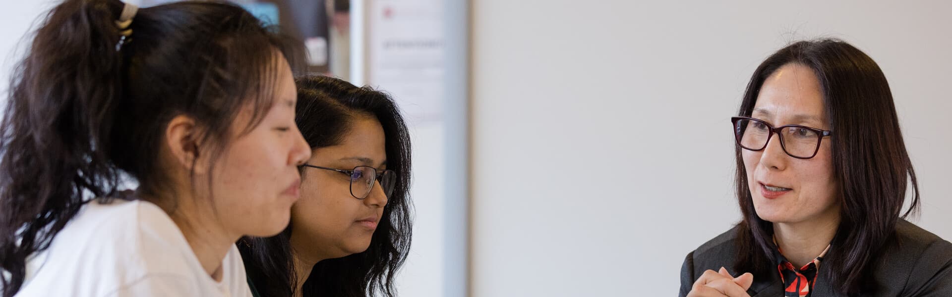 A woman speaking to two students