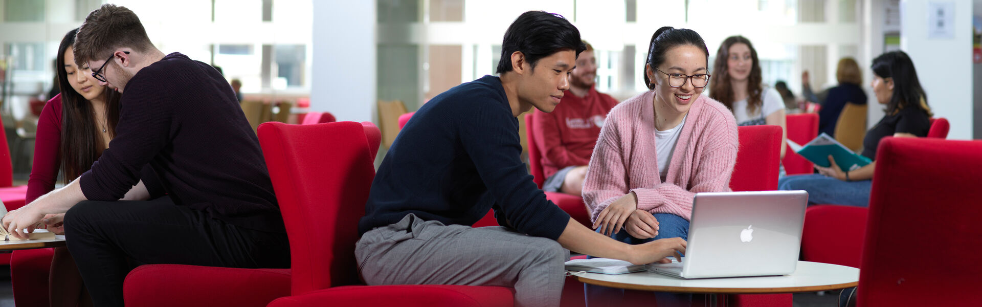 Two students sitting at a table looking at a laptop