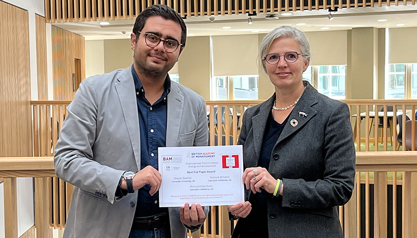 Shayan and Katy photographed with an award certificate in the Management School building