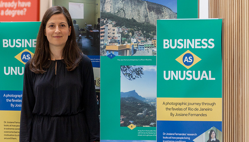 A woman standing in front of a banner stand with photographs on