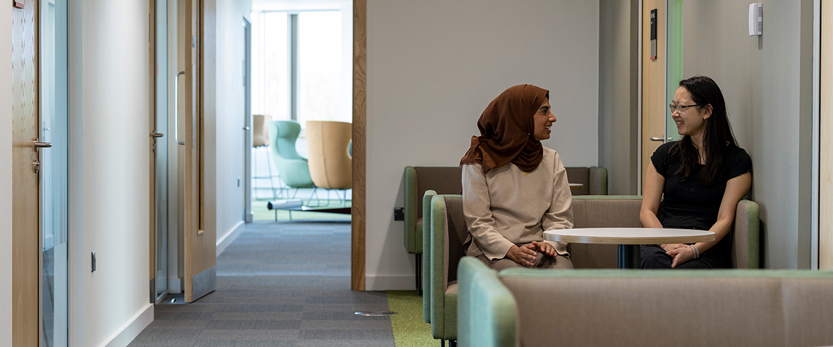 Ruqayyah and Alyssa in conversation in a Management School breakout space