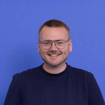 A smiling short haired man wearing glasses
