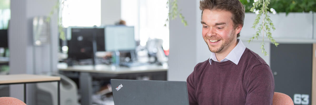 A member of staff working at a laptop in a modern office environment.