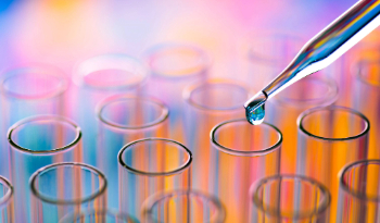A pipette dropping clear liquid into a test tube surrounded by other test tubes.