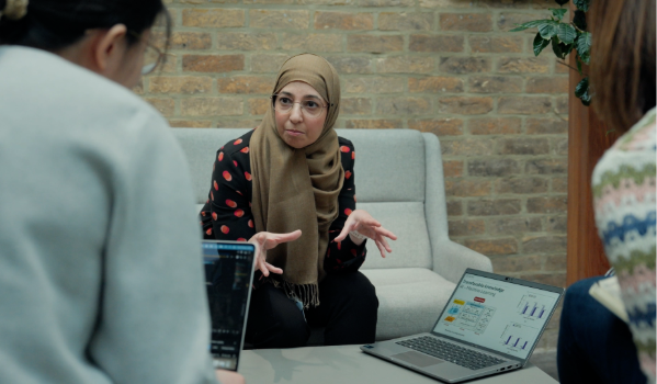 A woman talking to two other people presenting from a laptop.
