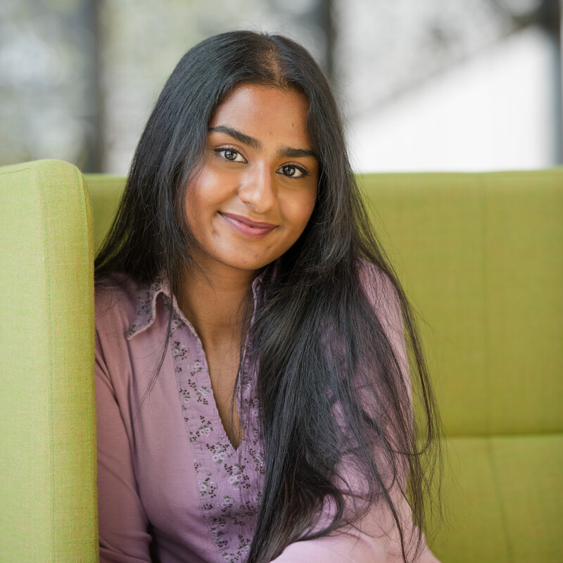 Medicine student Unna sitting on a green sofa looking towards the camera