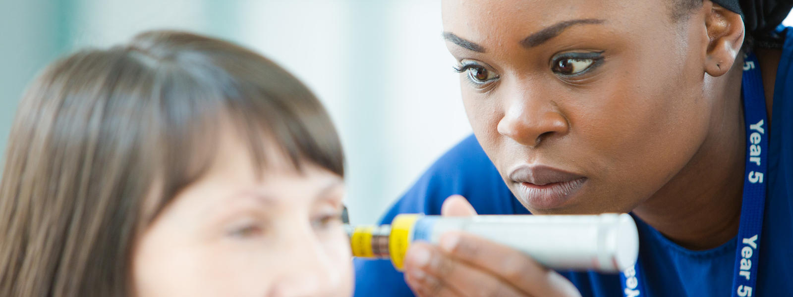 An image of two people - one is a nurse taking the temperature of another person