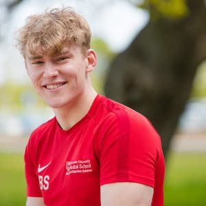 Image of Ben sitting outside near a tree, smiling