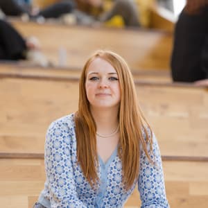 Briony sitting on steps in the  Health Innovation Campus at Lancaster University