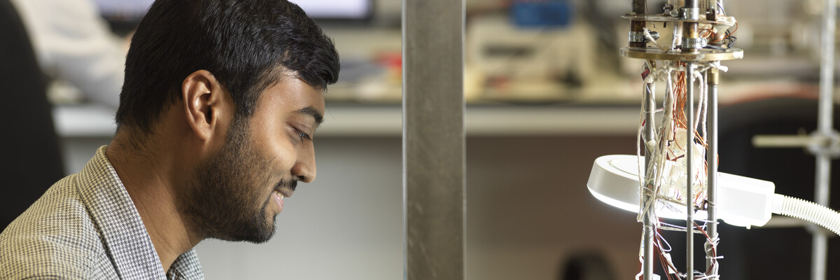 A man works in a laboratory building a complicated piece of machinery.