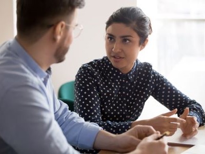 Two people sat at a table discussing a topic 