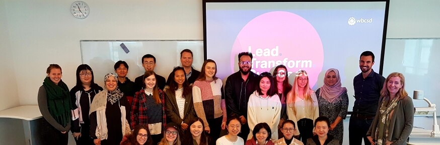 Large group of people standing in front of projection reading "Lead Transform Succeed" and WBCSD logo