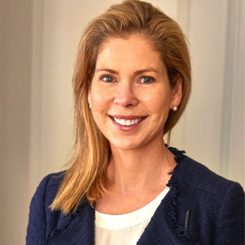 Head shot photo of Suzanne Johnson, she has long blonde hair and is smiling widely.