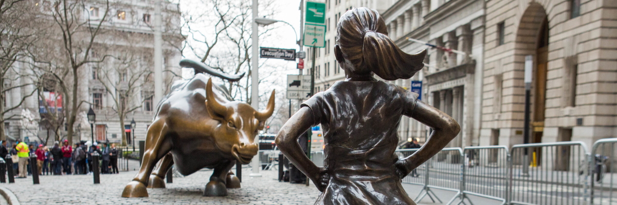 A statue of a young, fearless girl, standing resolute and facing the statue of a bronze bull
