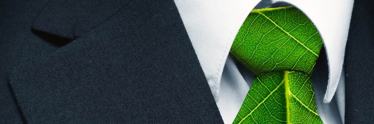Close up of a dark business suit, white shirt and tie that is made of bright green leaves
