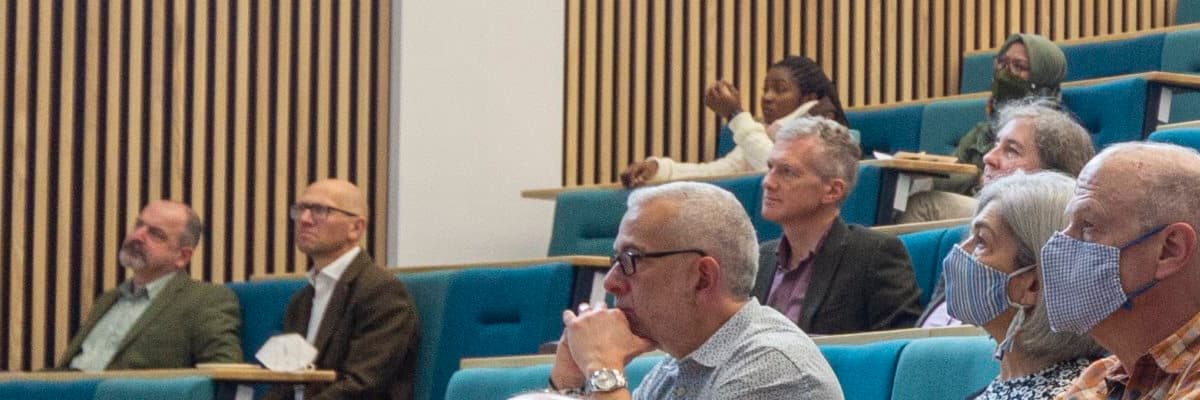 People paying listening to a talk in a lecture theatre