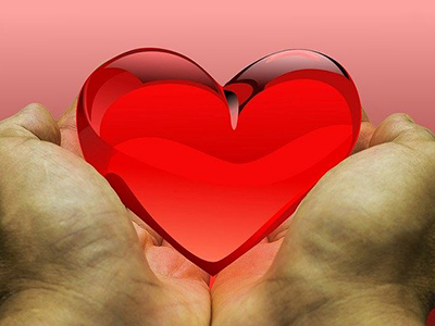 Two hands holding out a red glass heart