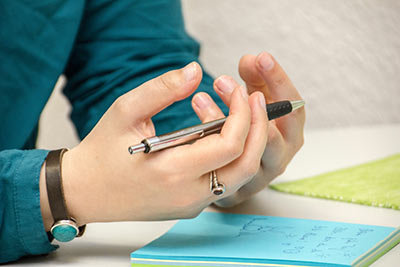 Hands holding a pen with pad