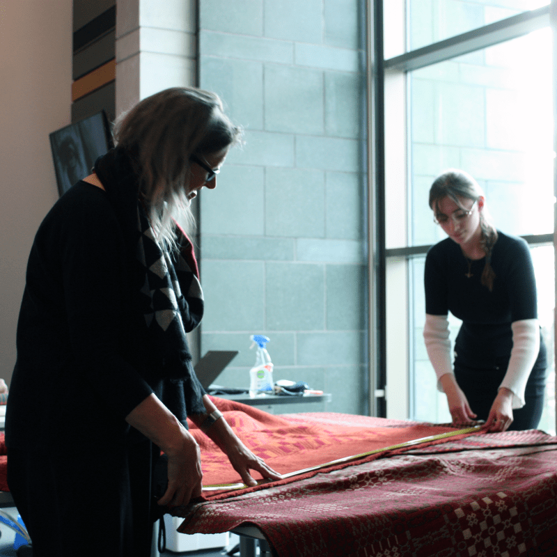 Volunteers measuring textiles for display
