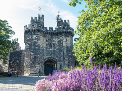 Lancaster Castle with purple flowers in the foreground, Photo Credit: Paula Robezneice