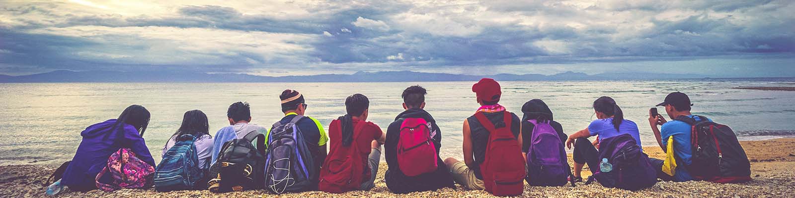 students with backpacks on beach 