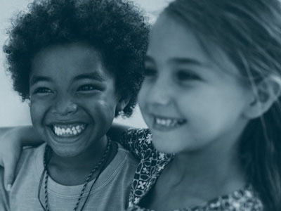 Two children smiling, one with an arm around the other