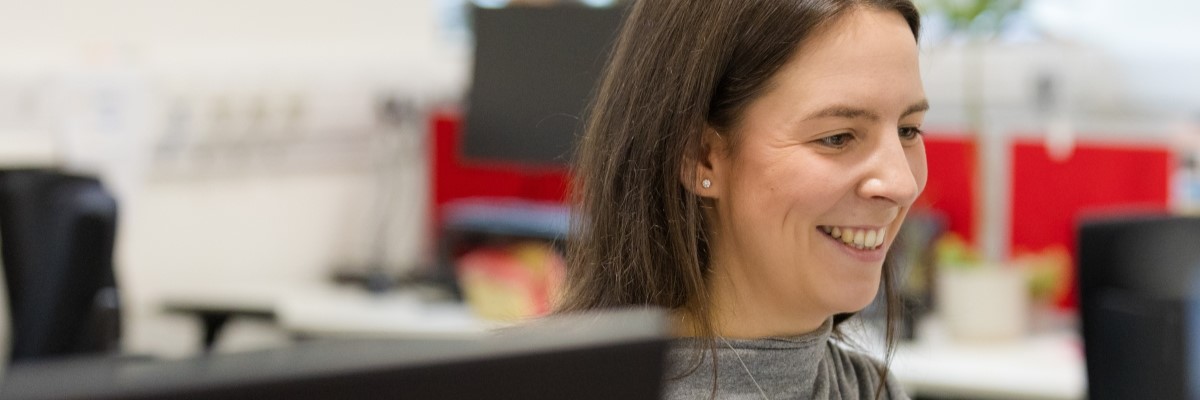 Student smiling whilst working at a computer