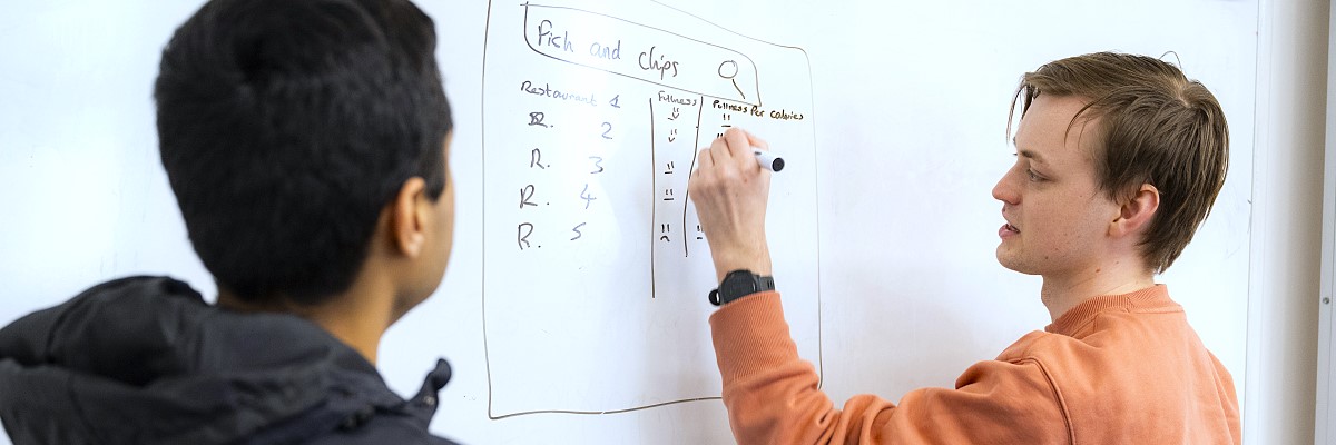 Student writing research on whiteboard