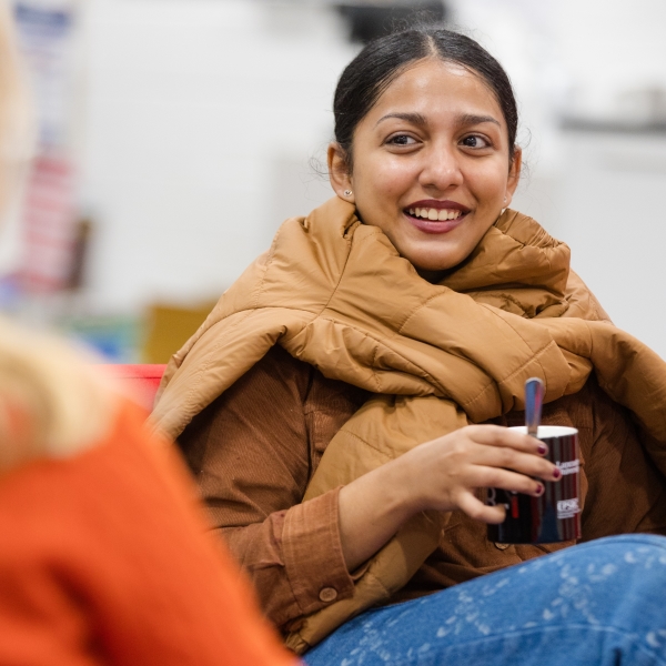 A student sat in the communal hub, smiling at a friend