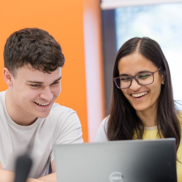 Image of two STOR-i students behind a laptop, smiling