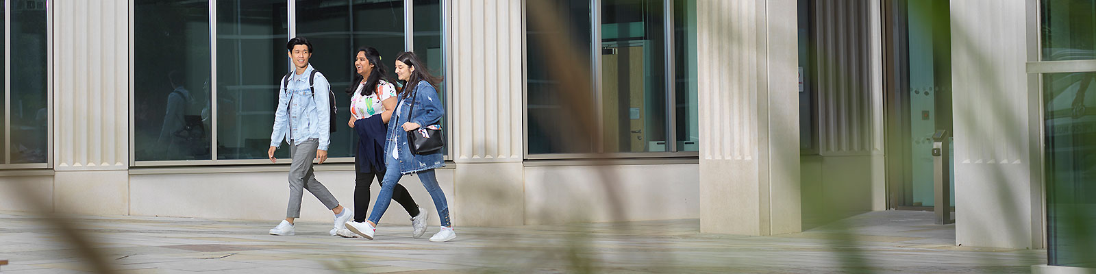 Three students walk past Lancaster's Management School building