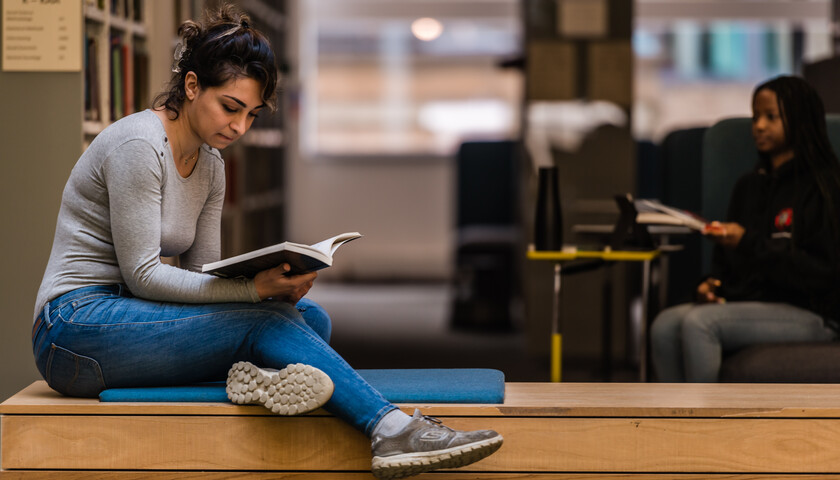 A student sits and reads in the library